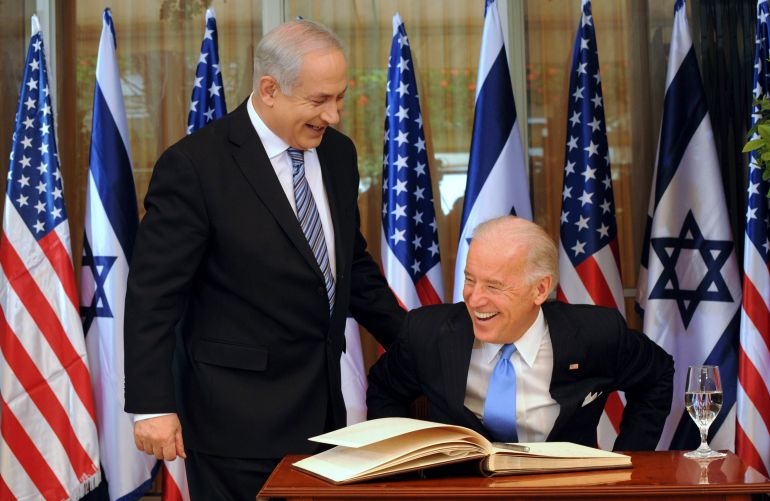 Benjamin Netanyahu looks over at a smiling Joe Biden