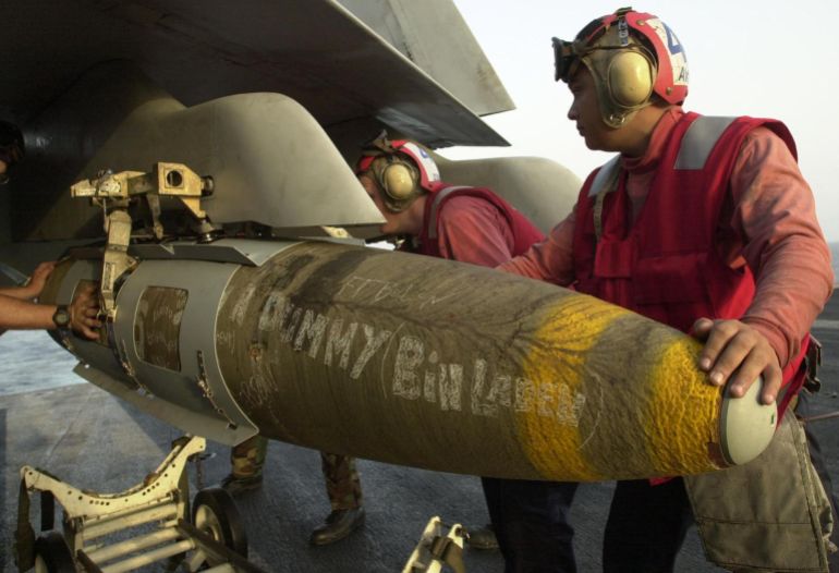 A 2,000 pound GBU-16 bomb is unloaded onto a US Navy F/A-18 Hornet parked 03 Novembeer 2001 on the aircraft carrier USS Theodore Roosevelt by unidentified Avionics Ordenance personnel. The Lasar guided bomb is typical of what pilots are dropping on Afghanistan, the military operations are being conducted from the USS Theodore Roosevelt which is afloat somewhere in the Arabian Sea with operation Enduring Freedom. AFP PHOTO/Mannie Garcia (Photo by MANNIE GARCIA / GANNETT/ARMY TIMES PUBLISHING CO / AFP)