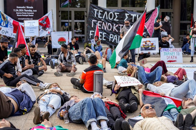 people lie on the ground at a protest with Palestinian flags