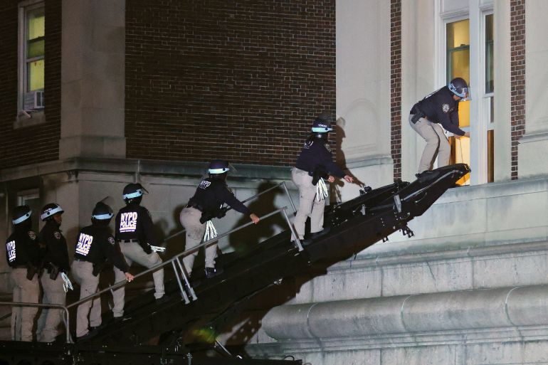 NYPD officers in riot gear break into a building at Columbia University, where pro-Palestinian students are barricaded inside a building and have set up an encampment, in New York City on April 30, 2024. - Columbia University normally teems with students, but a "Free Palestine" banner now hangs from a building where young protesters have barricaded themselves and the few wandering through campus generally appear tense. Students here were among the first to embrace the pro-Palestinian campus encampment movement, which has spread to a number of universities across the United States. (Photo by KENA BETANCUR / AFP)