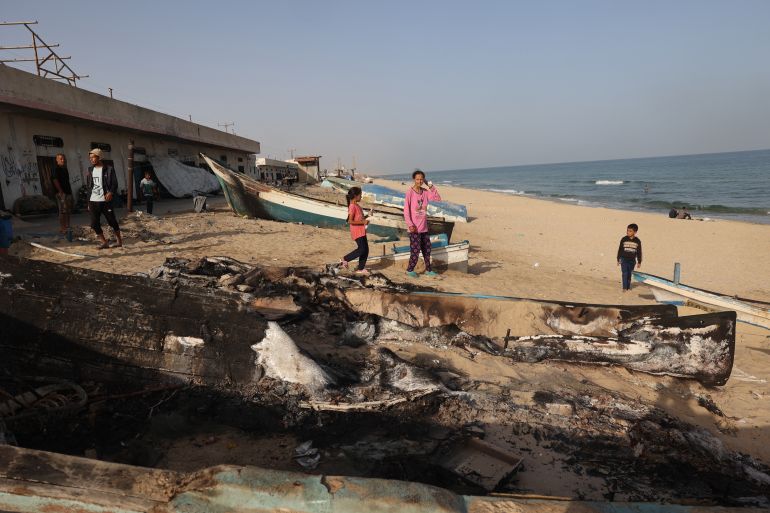 Palestinians inspect the damage around charred fishing boats hit by an Israeli airsrike on the Mediterranean coast of Rafah in the southern Gaza Strip on May 22, 2024, amid the ongoing conflict between Israel and the Palestinian Hamas group. (Photo by Eyad BABA / AFP)