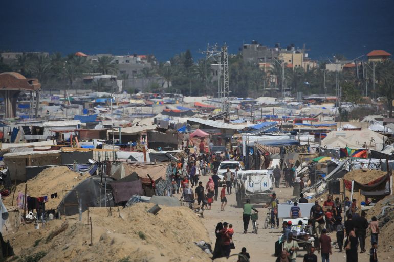 Displaced Palestinians walk on a road amid tents in the al-Mawasi camp where they took refuge, in Khan Yunis in the southern Gaza Strip