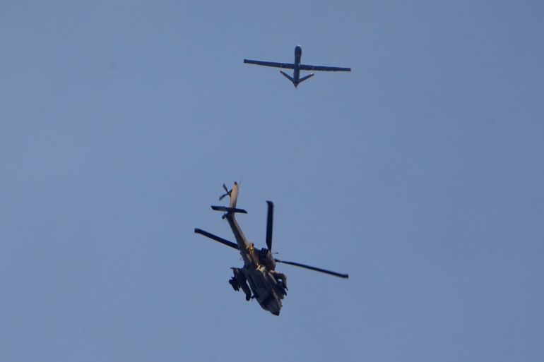 An Israeli military Apache helicopter and a drone fly close to the Gaza strip, as seen from southern Israel , Saturday, Dec. 16, 2023. (AP Photo/Ariel Schalit)