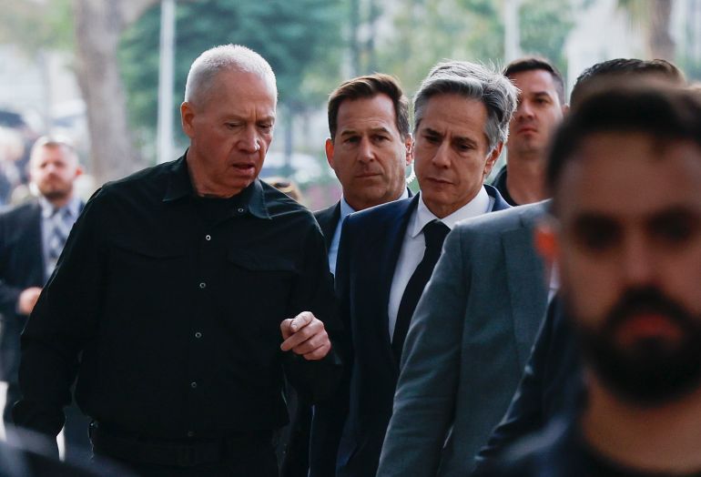 a man wearing all black speaks to a man in a suit