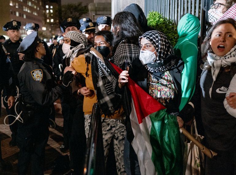 a police officer confronts people holding arms at a protest