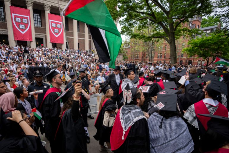 Graduating students hold Palestinian flags and chant as they walk out in protest over the 13 students who have been barred from graduating due to protest activities, during commencement in Harvard Yard, at Harvard University, in Cambridge, Mass., Thursday, May 23, 2024. (AP Photo/Ben Curtis)